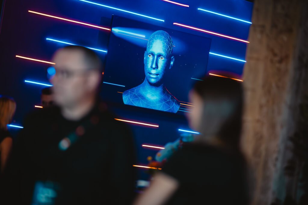 Der blaue Avatar und Moderator MuVi spricht mit Gästen des MuV Forward 25